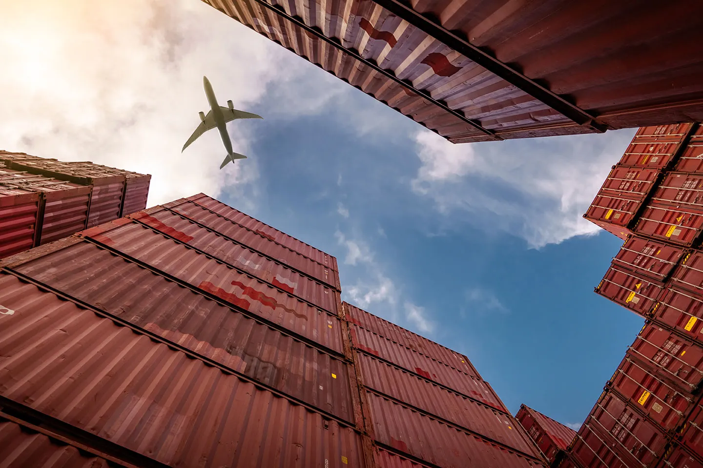 Aircraft flying over stacked shipping containers