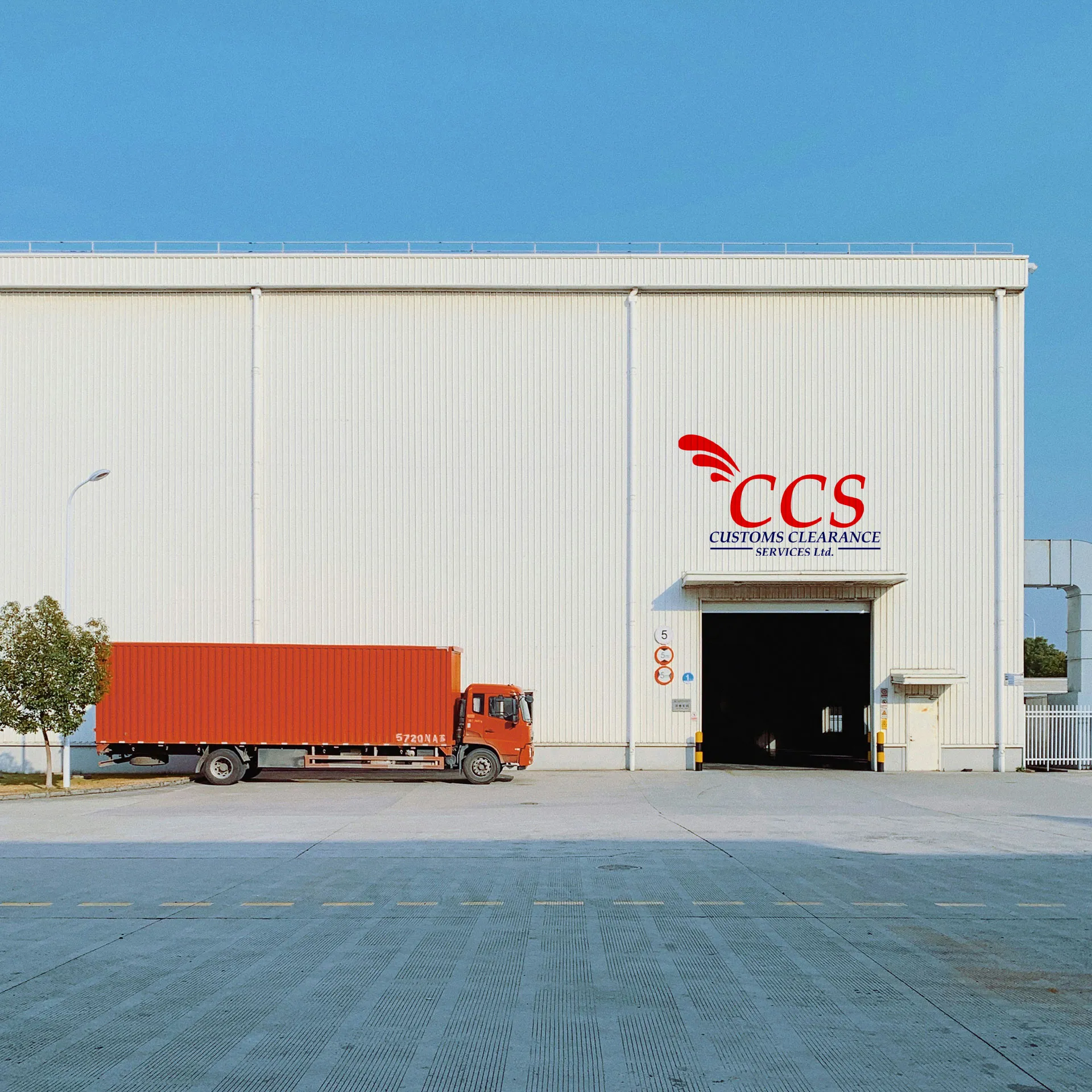 CCS warehouse with the company logo above the loading bay and a container truck parked outside